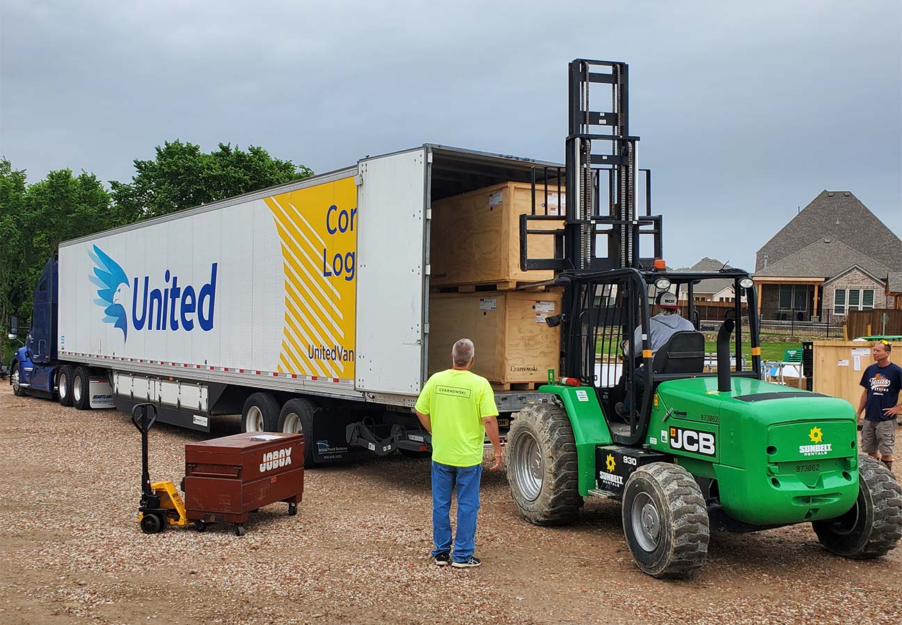 Corrigan Logistics employees unloading creates with forklift off of truck