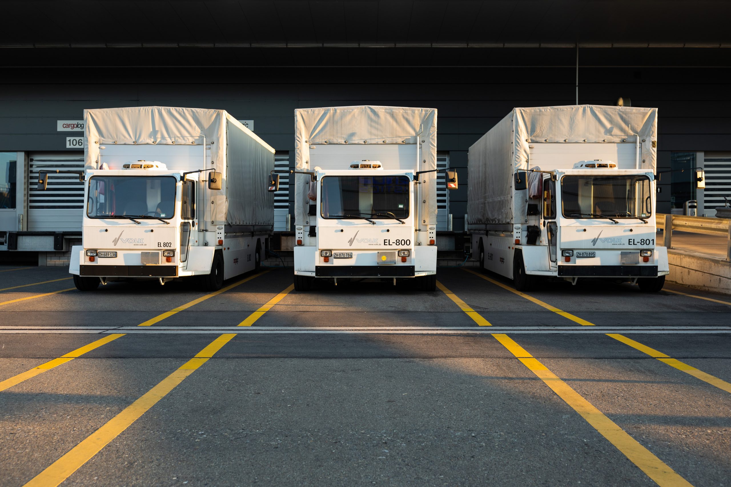 Three white glove service transport trucks in a parking lot